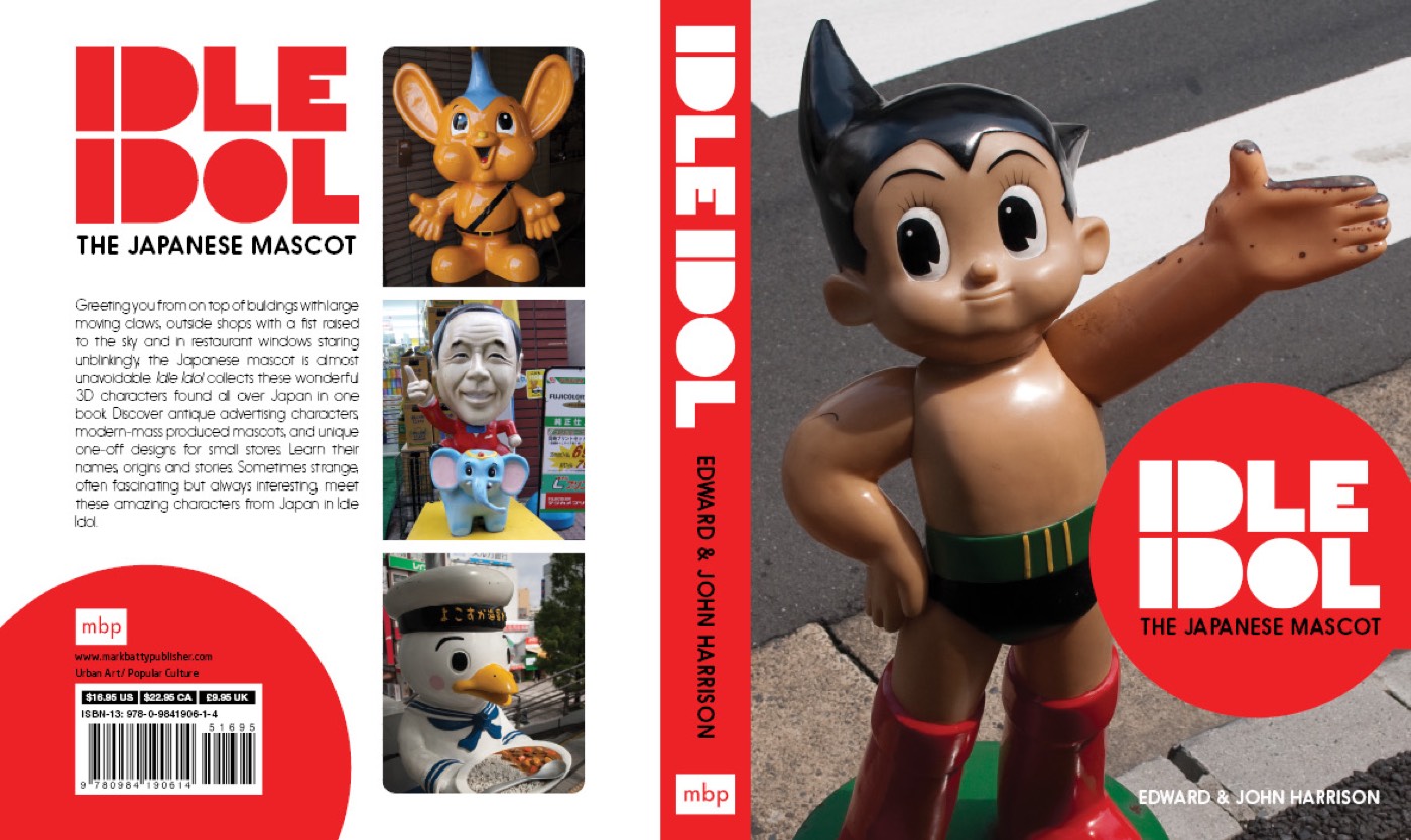The Idle Idol book cover: an Astro Boy statue on a street crossing, with the red circle logo, spine and back cover showing more mascots.