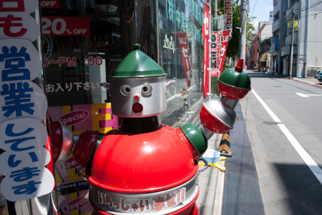 King Robo, a silver and orange retro robot statue standing on the pavement.