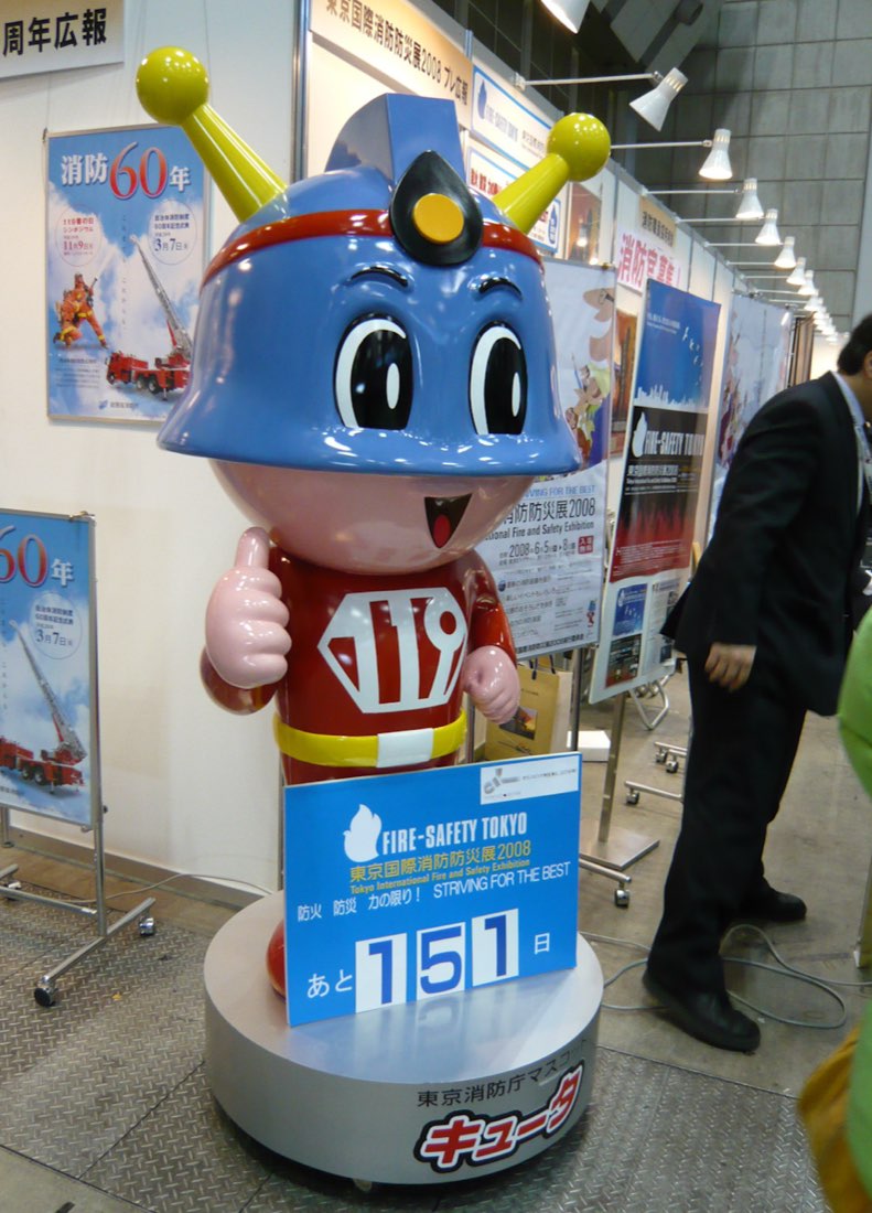 Kyūta, the Tokyo fire department mascot: a white-faced figure in a red suit and blue helmet with yellow antennae, marked 119.