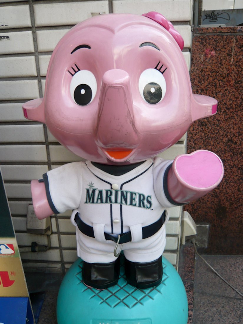 A pink Sato elephant mascot wearing a Seattle Mariners baseball shirt.
