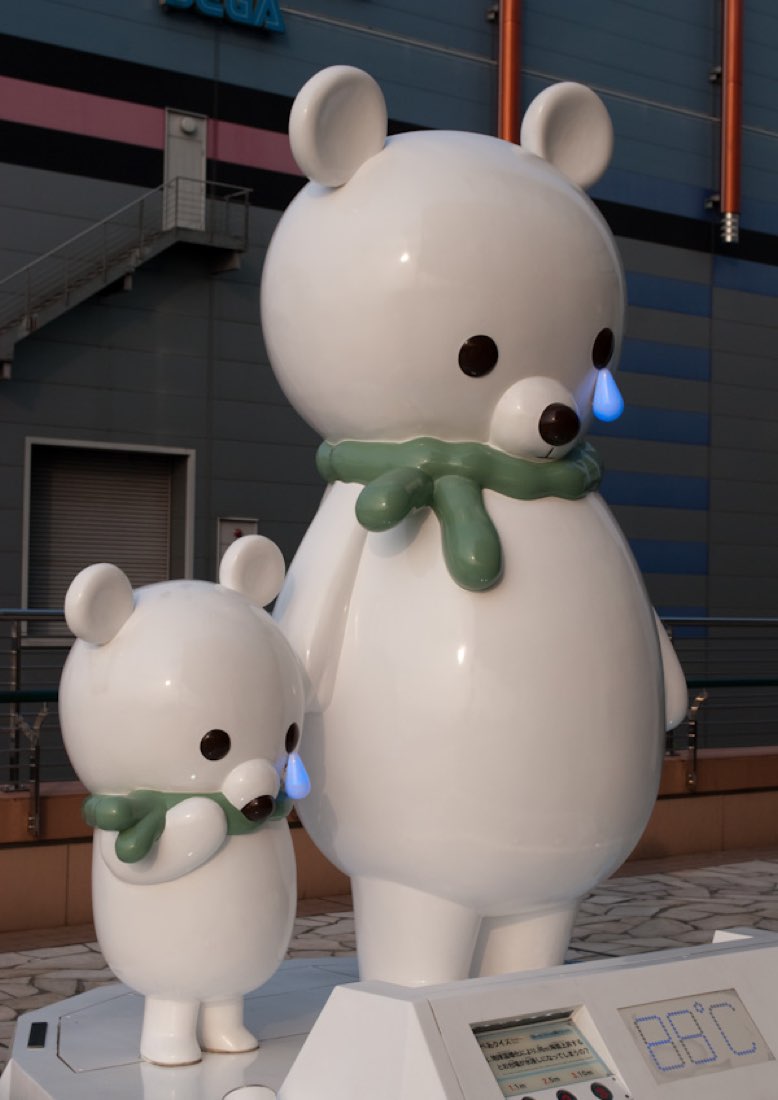 Two white polar bear statues, one large and one small, each with a single blue tear on its cheek.