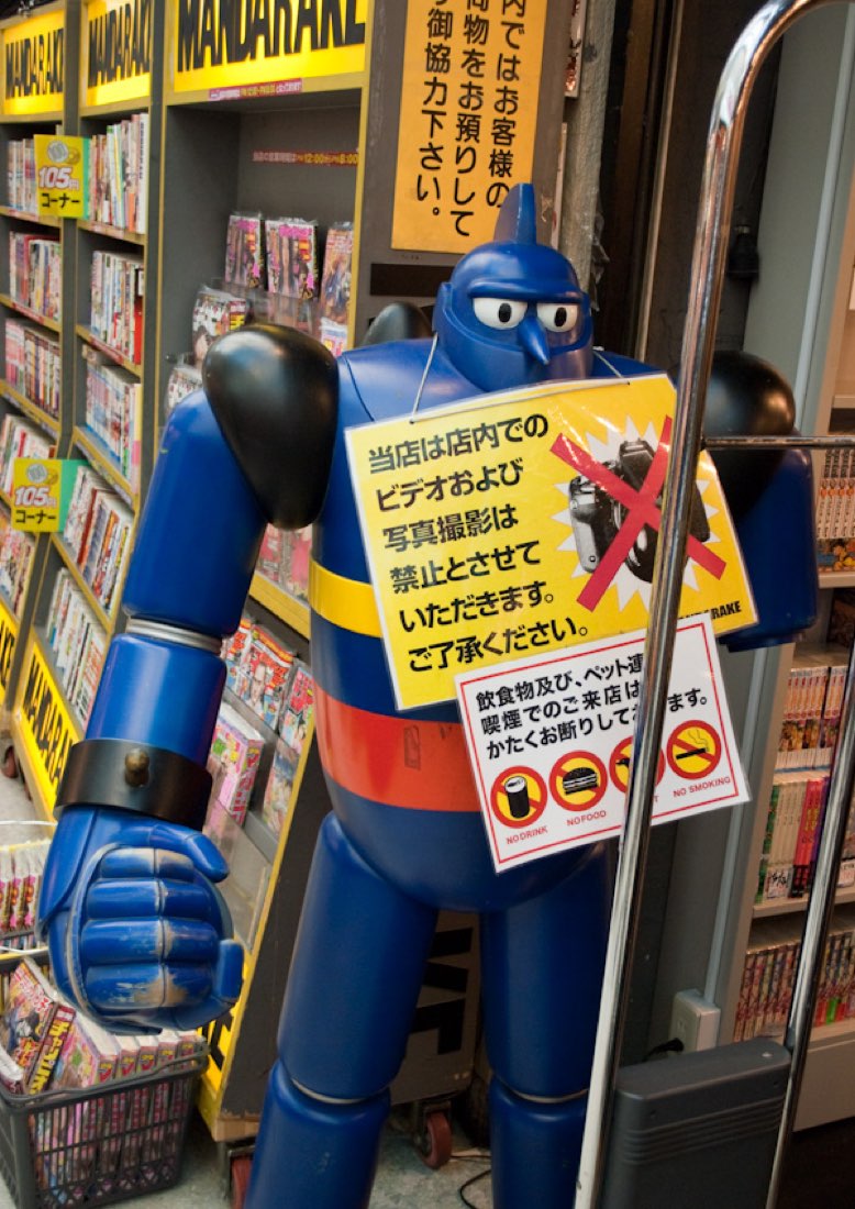 A blue Tetsujin 28-gō robot statue with a sign round its neck asking customers not to take photographs.