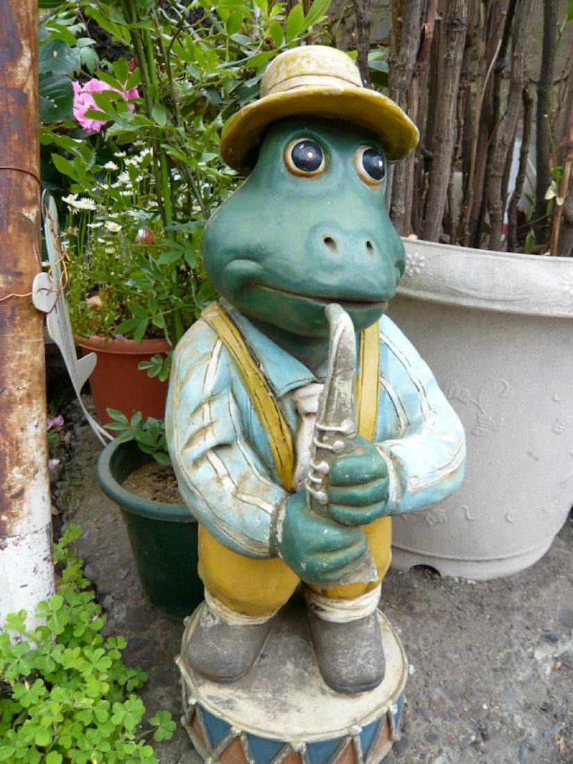 A carved turtle standing upright in a flat cap and jacket, holding a clarinet.